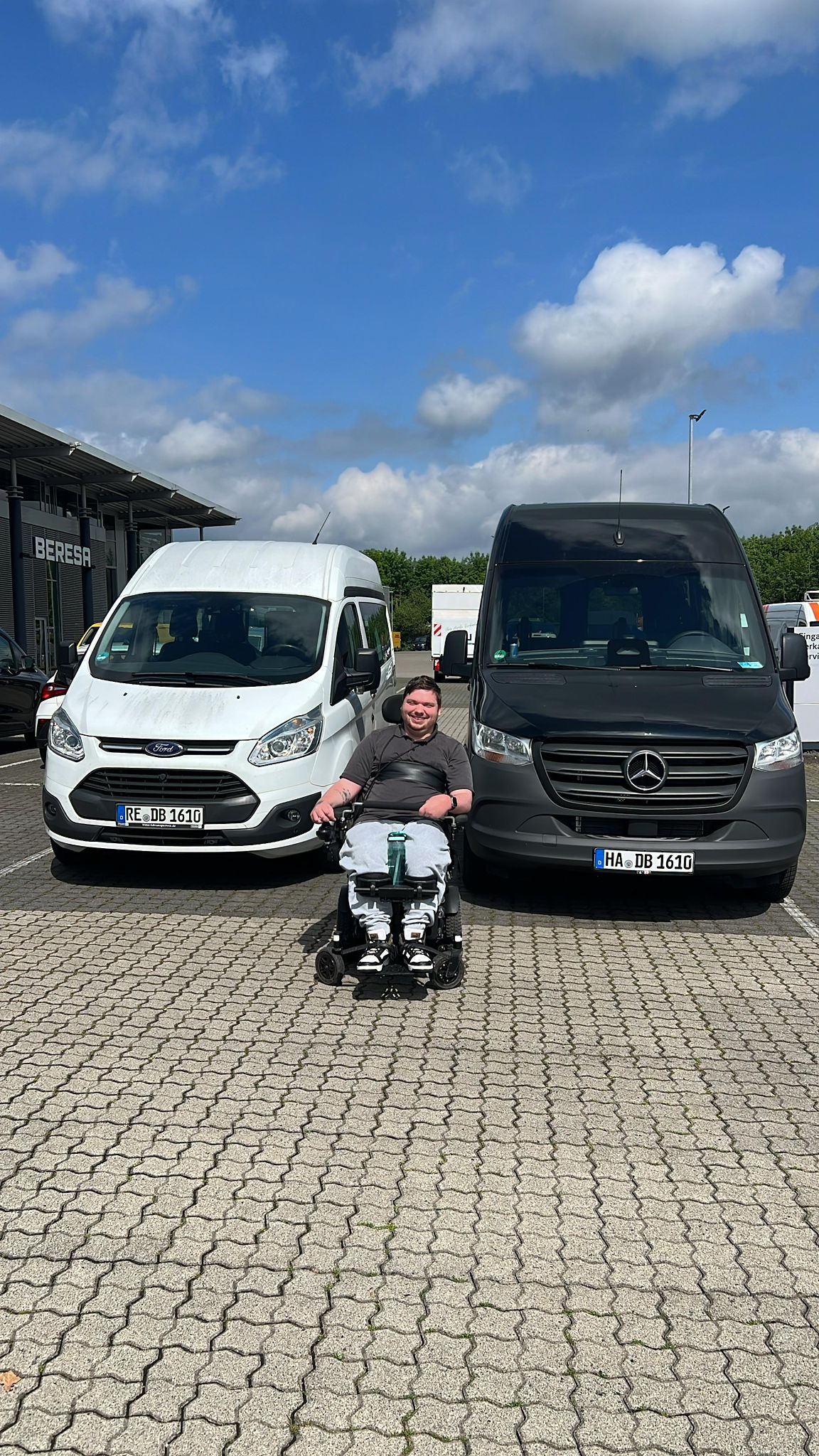 Dylan Böse im Rollstuhl zwischen dem alten Ford Transit und dem neuen Mercedes Sprinter